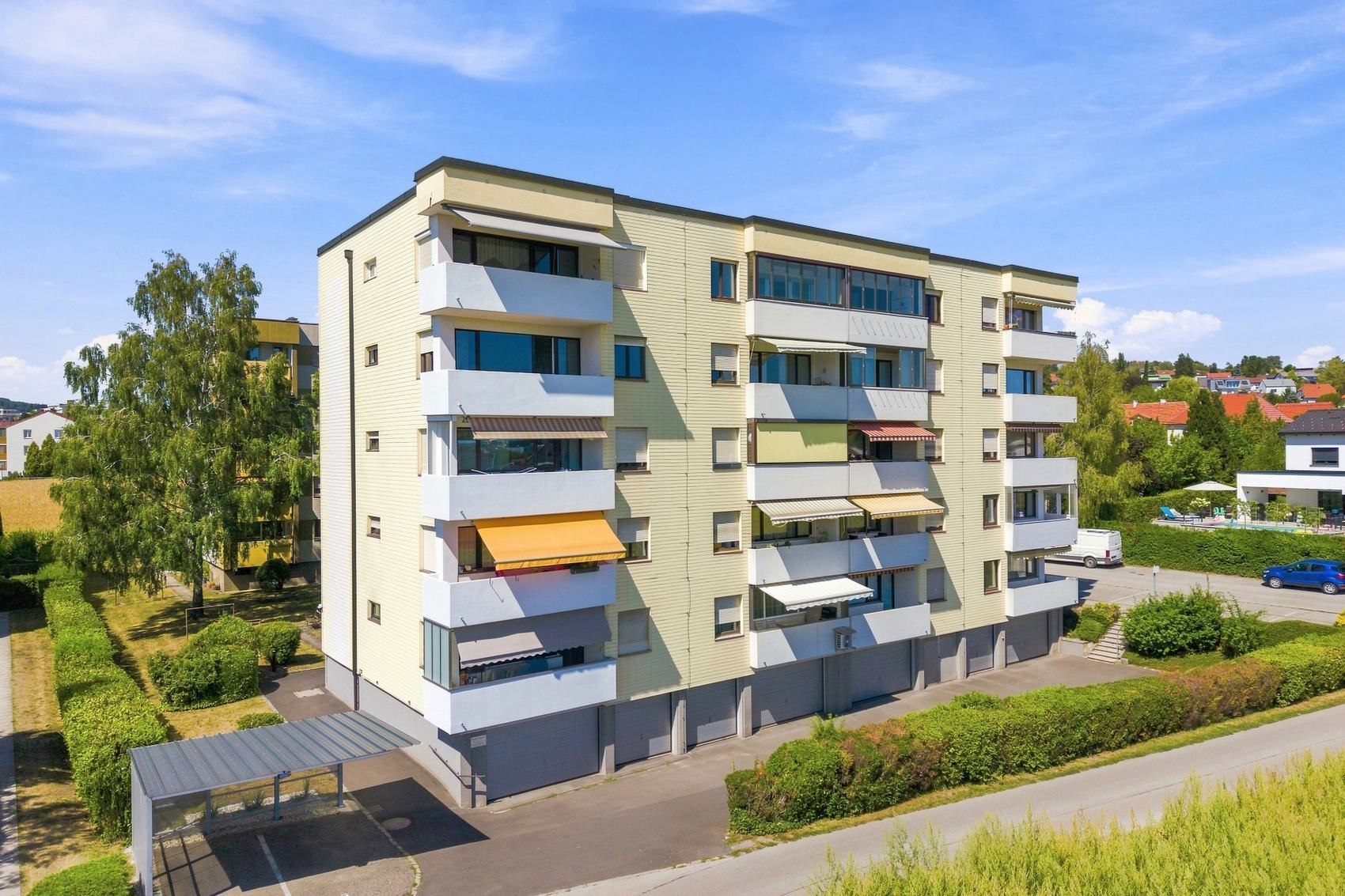 Wohnblock mit gelben Markisen und Bäumen