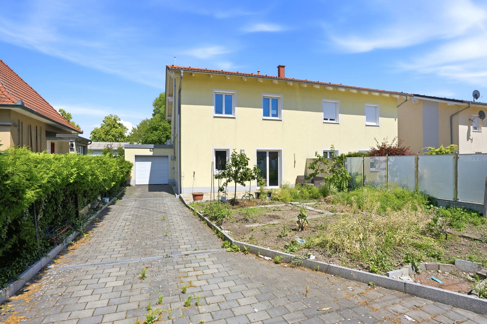 Haus mit blauen Fensterläden und gepflasterter Einfahrt